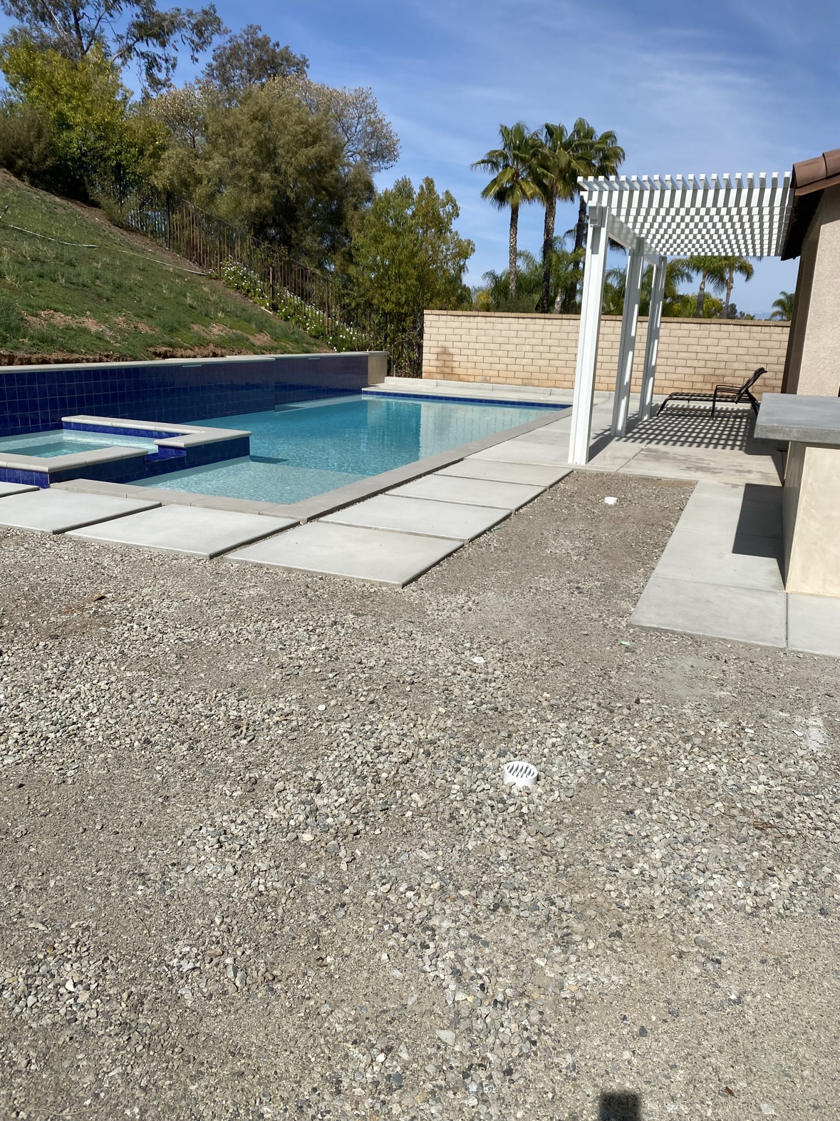 Curved concrete patio with seat walls, outdoor kitchen, and fire pit