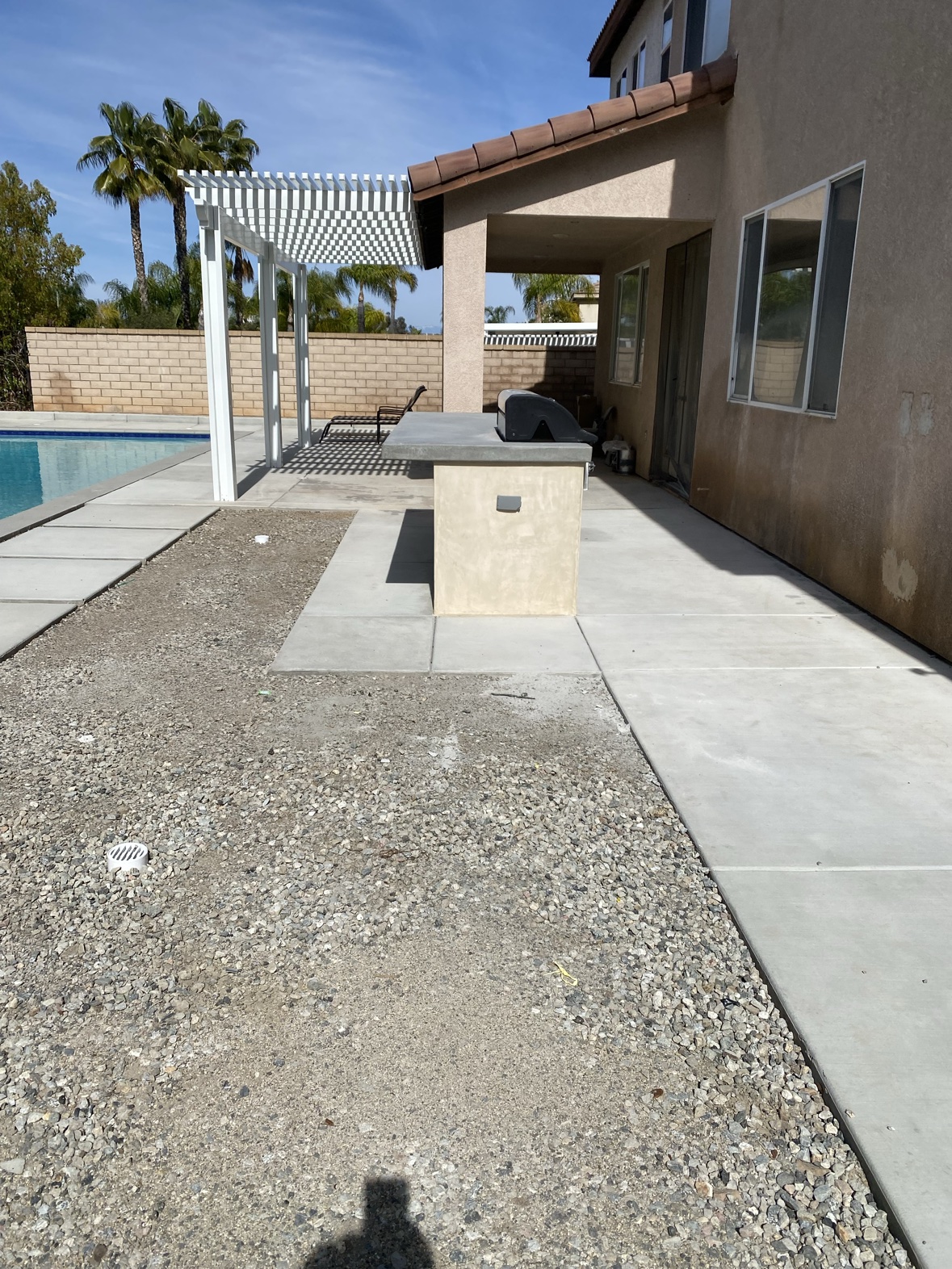 Backyard patio with outdoor kitchen island, fire pit, and seat walls
